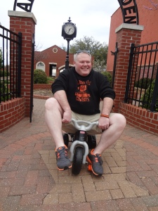 Price Purvis, President of Guthrie Kiwanis Club, tries out a scooter in advance of the “Big Wheels” race, scheduled for Friday, April 19th at 5PM at Harrison and 1st St. in downtown Guthrie.