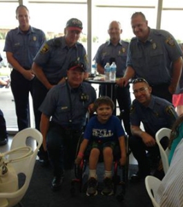 Elijah Robles is surrounded by OKC Firefighters at the MDA premier for families and sponsors.