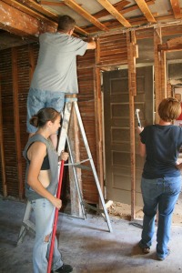 Gary Byte climbs a ladder while Madison Birdwell sweeps and Angie Byte hammers as they assist their neighbor. Over a dozen of neighbors have been seen lending their help.
