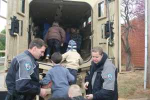 School Resource Officer Anthony Gibbs (left) and Detective Jeremy Thorne help children into the MRAP.
