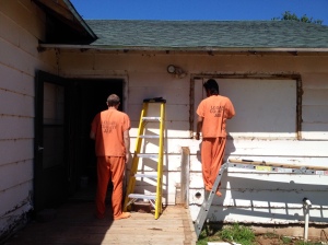 Two county trustee inmates work on the outside of the lake house as part of the renovation of the home.