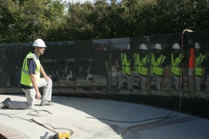 On Oct. 28, sculptor Joel Randell notices the polished granite sections make great mirrors on the walls surrounding the concrete foundation that will hold his bronze statues for dedication Veterans Day at Patriot Park in Del City, Okla. Photo by Darl DeVault.